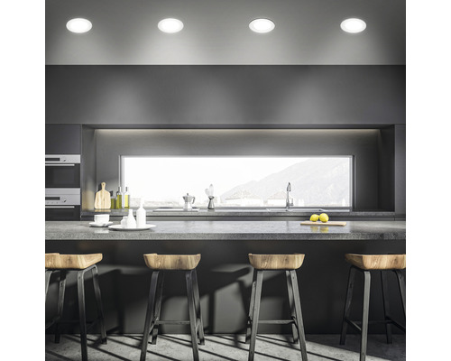 Moderne keuken met kookeiland, barkrukken en inbouwspots in het plafond.