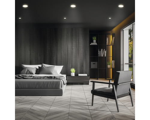 Slaapkamer met bed, fauteuil en boekenkast in een donker ontwerp