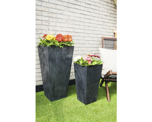 Twee kunststof plantenbakken met bloemen op een terras.