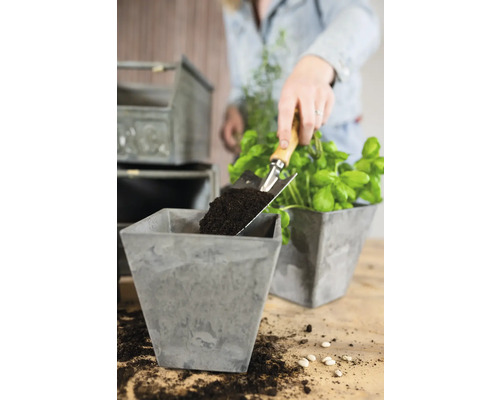 "Een persoon vult een vierkante plantenbak met aarde met een schep