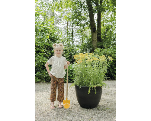 Meisje met spade naast een plantenbak in de tuin.