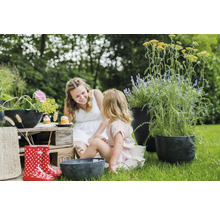 Tuinscene met moeder, kind, bloemen, plantenbakken en accessoires voor buiten.