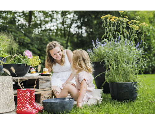Tuinscene met moeder, kind, bloemen, plantenbakken en accessoires voor buiten.