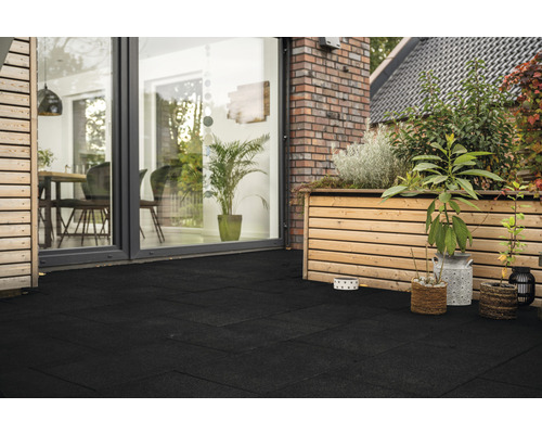 Terras met zwarte terrastegels, houten beplanting en uitzicht op het huis