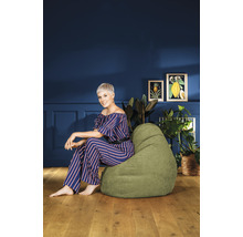 Vrouw zit op een groene zitzak in de woonkamer.