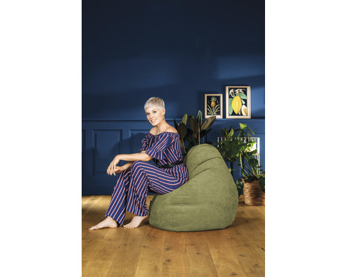Vrouw zit op een groene zitzak in de woonkamer.