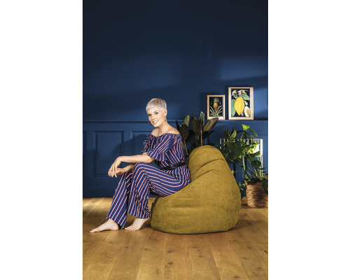 Vrouw zit op een groene zitzak in een lichte kamer
