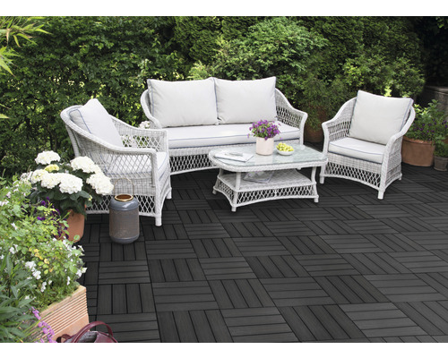 Terras met donkere terrastegels en rotan zitgroep in de tuin