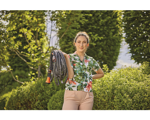 Vrouw houdt een tuinslang vast in een tuin.