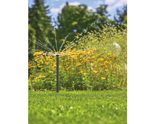 Tuinscène met gazonsproeier die water sproeit
