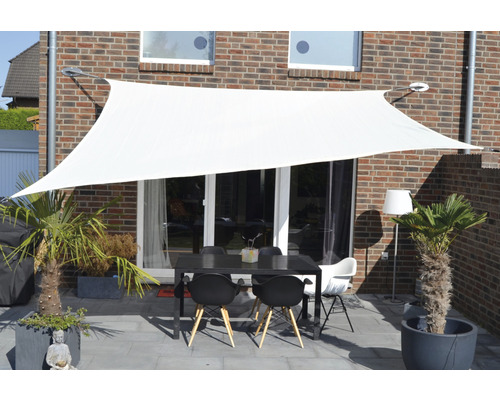 Wit zonnescherm boven een terras met tafel en stoelen