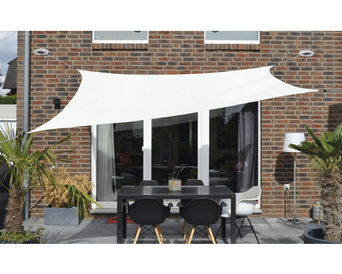 Terras met schaduwdoek, tafel en stoelen voor een huismuur