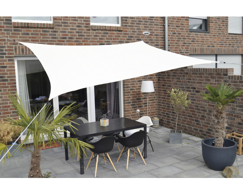 Terras met schaduwdoek, tafel en stoelen voor een bakstenen gebouw