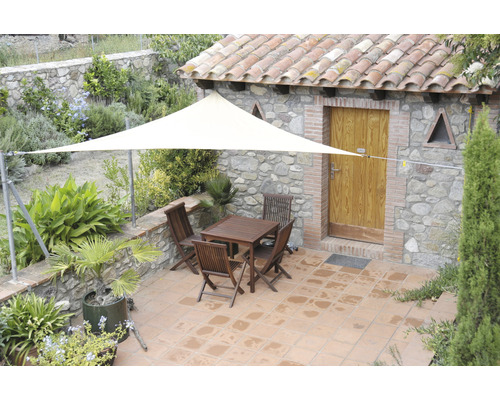 Buitenkant met driehoekig zonnescherm, tafel en stoelen op een terras.