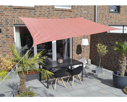 Terras met zonnescherm, tafel en stoelen voor een bakstenen gebouw