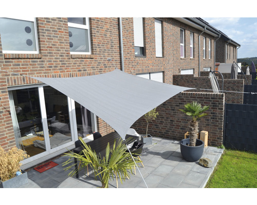 Vierkant zonnescherm boven een terras met tafel en planten