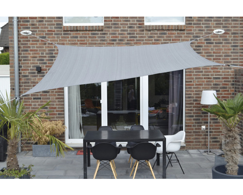 Terras met zonnescherm, tafel en stoelen voor een huismuur