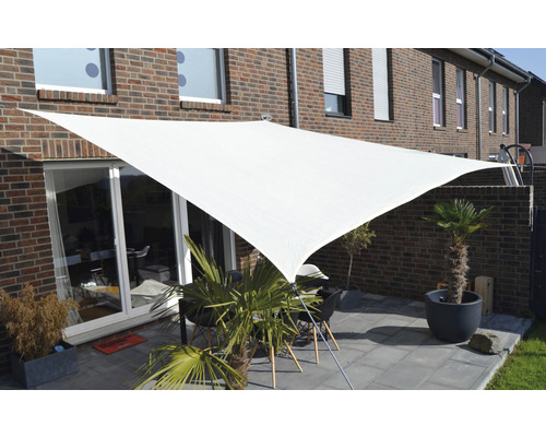 Terras met driehoekig zonnescherm en tuinmeubelen voor een bakstenen huis