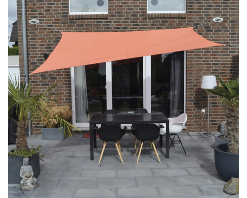 Terras met schaduwdoek, tafel en stoelen voor een huismuur