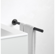 Zwarte handdoekhouder met handdoek gemonteerd aan een witte muur