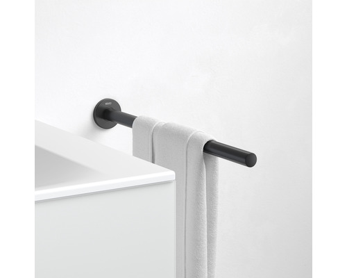 Zwarte handdoekhouder met handdoek gemonteerd aan een witte muur