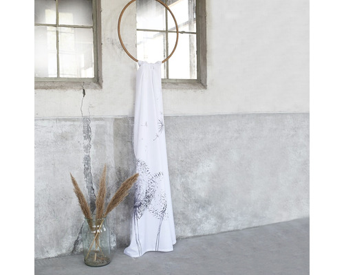 Decoratieve sjaals met paardenbloemmotief, opgehangen aan een houten ring, naast een vaas met siergras