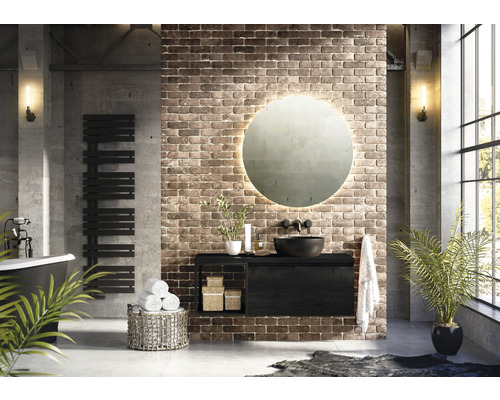 Moderne badkamer met wastafel, ronde spiegel, handdoekradiator en badkuip voor een bakstenen muur