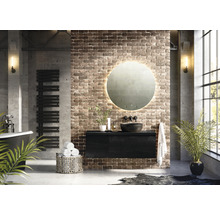 Moderne badkamer met vrijstaand bad, handdoekradiator, wastafelonderkast, ronde spiegel met verlichting en bakstenen muur