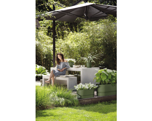 Tuinomgeving met parasol, tafel, bank en beplante bloembakken.