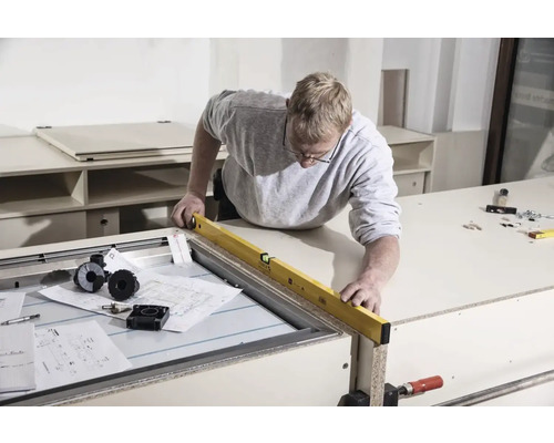 Ambachtsman met waterpas aan werkbank