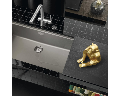 Spoelbak en keukenkraan in een moderne keuken met zwarte wandtegels.