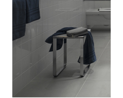 Badkamer met een metalen kruk, handdoeken en een toilettas