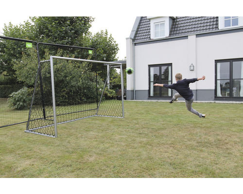 Voetbaldoel met voetbal op gras en persoon die schiet