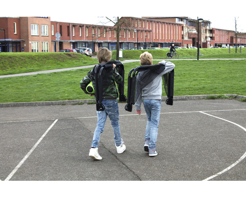 Twee kinderen dragen opgevouwen bolderkarren op een schoolplein.