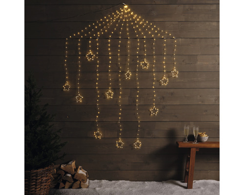 Decoratieve lichtslinger met sterren voor een houten wand, met boom, houtblokken en champagneglazen