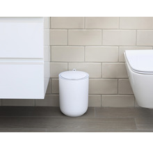 Scene van een badkamer met een witte cosmeticaemmer met deksel