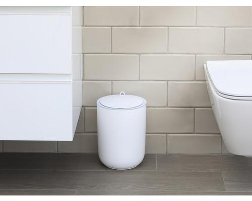 Scene van een badkamer met een witte cosmeticaemmer met deksel