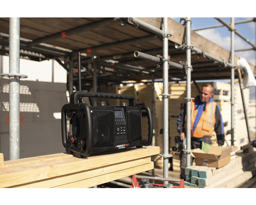 Bouwradio op een houten oppervlak met een bouwvakker op de achtergrond