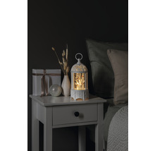 Decoratief nachtkastje met cadeau, vaas, decoratieve bal en verlichte sneeuwbol