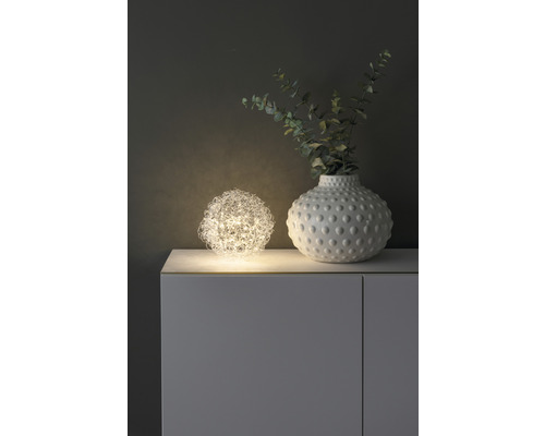 Decoratieve scène met bolvormige lamp en vaas op een kast