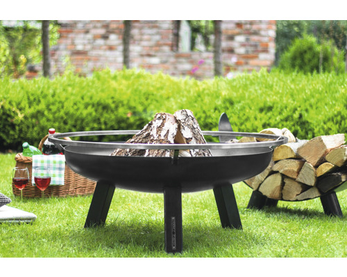 Vuurschaal op gazon met hout en picknickmand