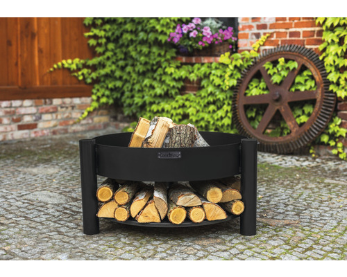 Zwarte vuurschaal met houtopslag in de tuin