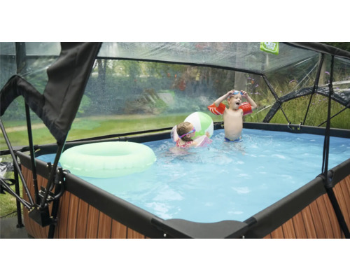 Zwembad met overkapping, kinderen spelen met zwemband en bal in het water