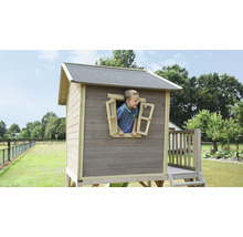 Houten speelhuis met jongen bij het raam in de tuin