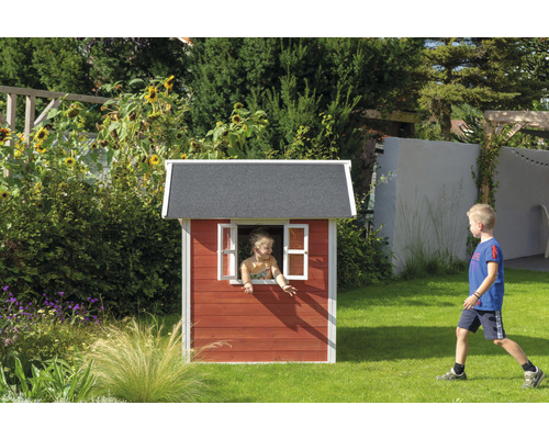 Kind in houten speelhuis in de tuin