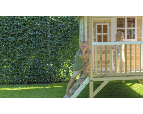 Kinderen spelen in een houten speelhuis in de tuin.