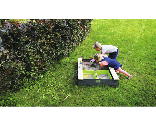 Twee kinderen spelen in een zandbak in de tuin.