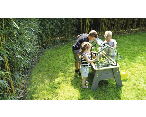 Kinderen tuinieren met een plantenbak op poten in de tuin.