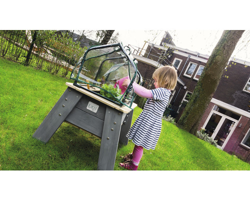 Kind giet planten in verhoogde tuinbak met kasopzet in de tuin