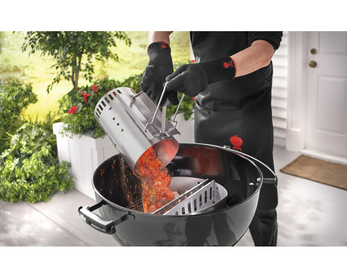 Persoon giet gloeiende barbecuekolen met een aanmaakkorf in een houtskoolbarbecue